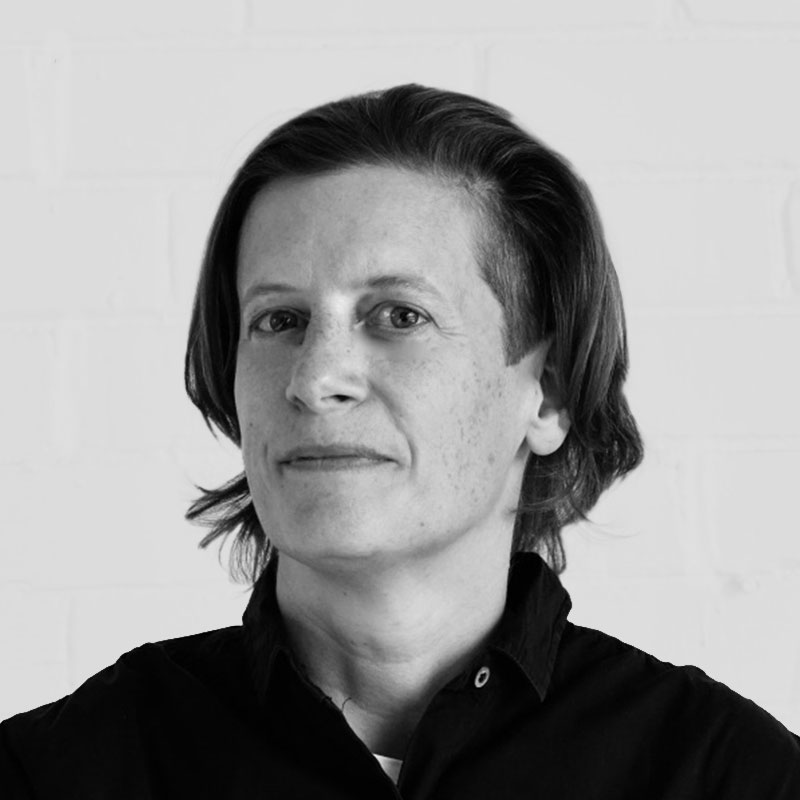 Portrait en noir et blanc de l'artiste Karen Vanderborght cadré aux épaules. Elle porte les cheveux courts et une chemise noire. Pour la résidence de recherche du Chantier IA de Sporobole.